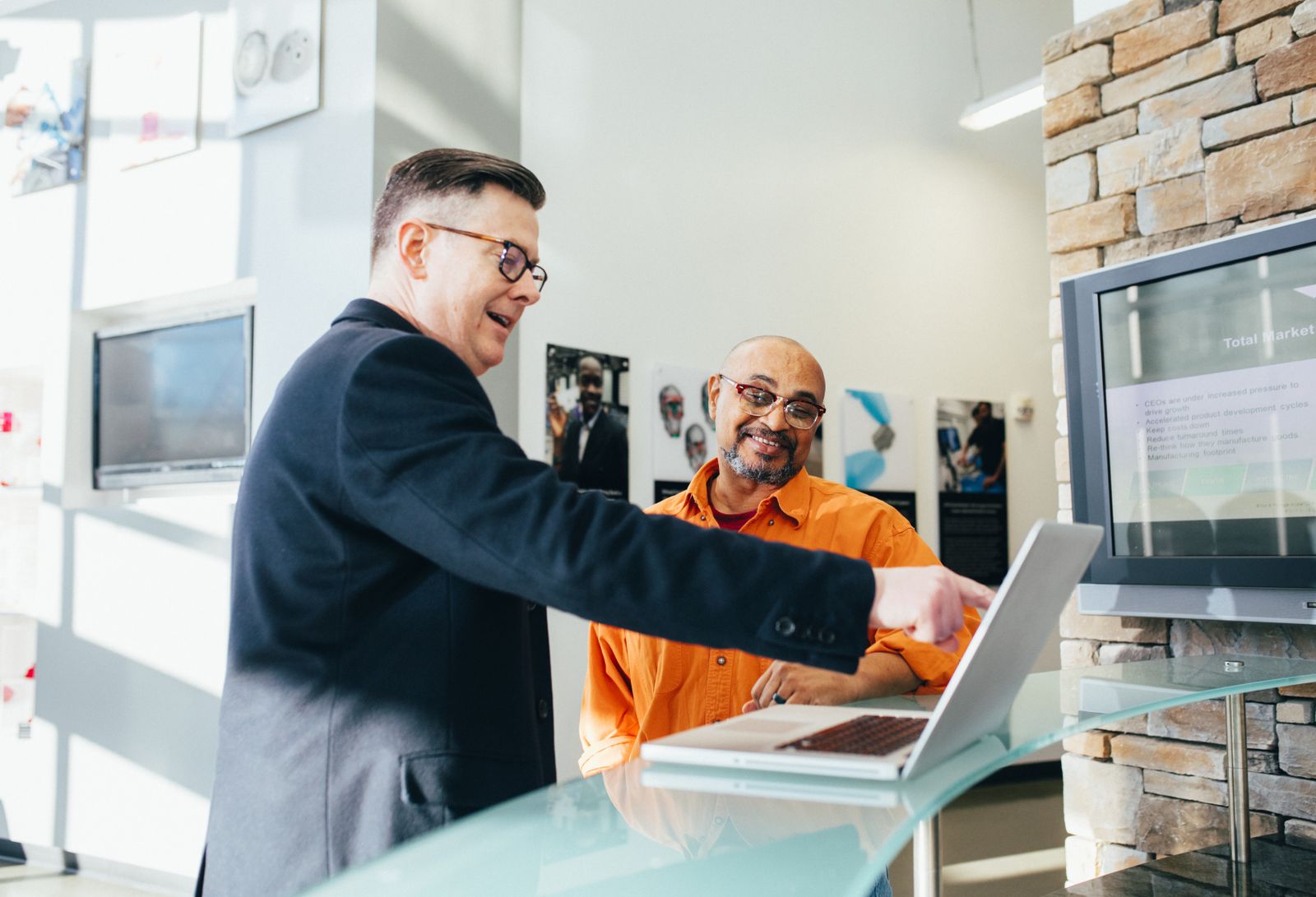 Two business people discussing information on a laptop.