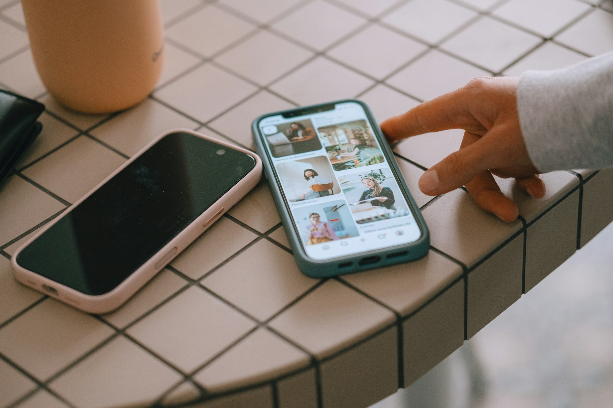 A person browsing pictures on a phone beside another phone.