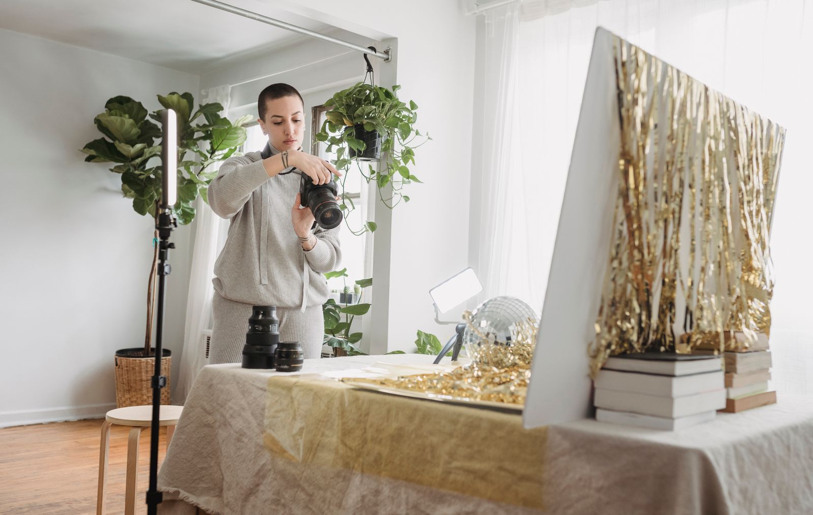 A photographer checking a camera beside lighting and a gold product backdrop.
