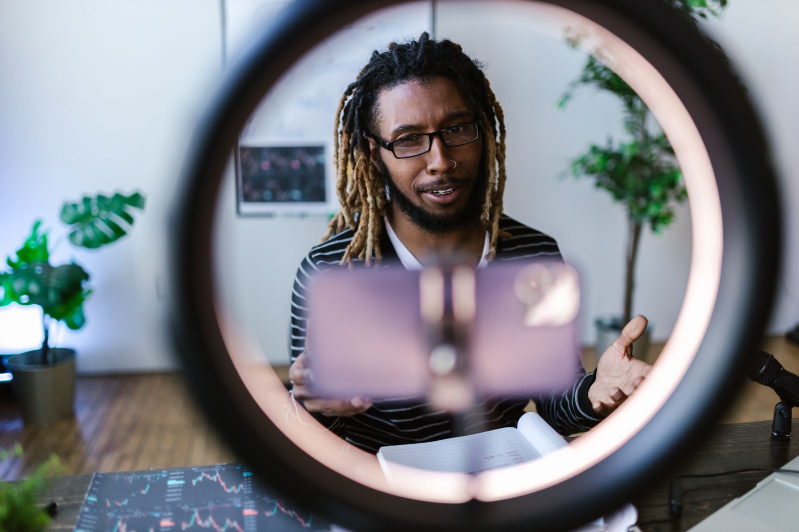 A small-business creator filming a video on a phone through a ring light.